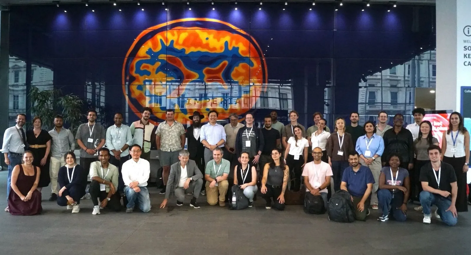Group photo of around forty summer-school participants in front of a large brain-scan artwork in Imperial's entrance hall.
